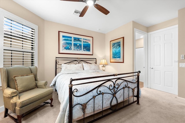 carpeted bedroom with visible vents, baseboards, and a ceiling fan