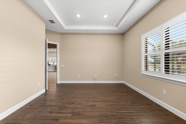 empty room featuring baseboards, visible vents, a tray ceiling, recessed lighting, and dark wood-type flooring