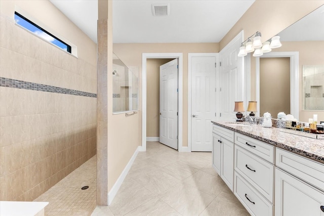bathroom with vanity, visible vents, baseboards, a walk in shower, and tile patterned floors