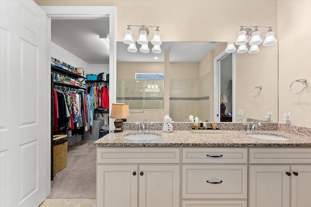 bathroom with double vanity, a spacious closet, a walk in shower, and a sink