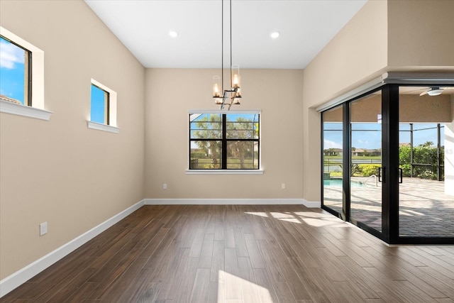 unfurnished dining area featuring recessed lighting, baseboards, dark wood-type flooring, and a chandelier