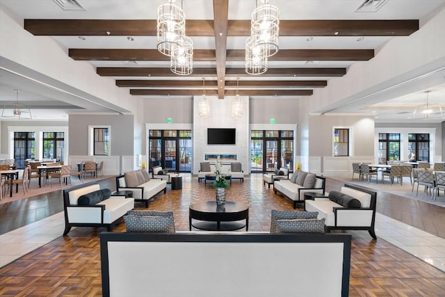 living room with beam ceiling, a decorative wall, a wainscoted wall, and a chandelier