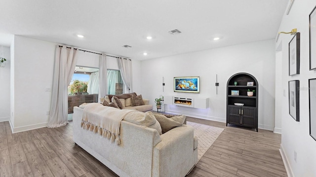 living room featuring built in shelves and light hardwood / wood-style floors