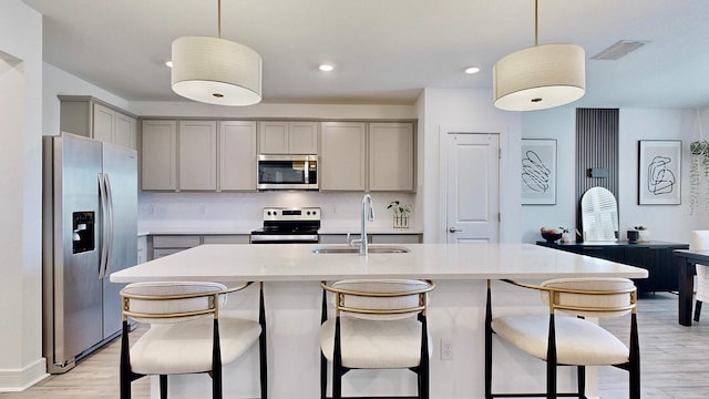 kitchen featuring pendant lighting, an island with sink, appliances with stainless steel finishes, and sink