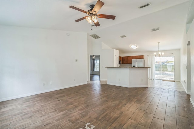 unfurnished living room with ceiling fan with notable chandelier and vaulted ceiling