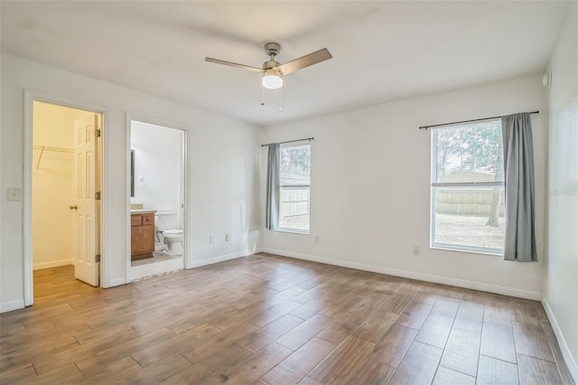 unfurnished bedroom featuring a closet, a walk in closet, ensuite bathroom, and ceiling fan