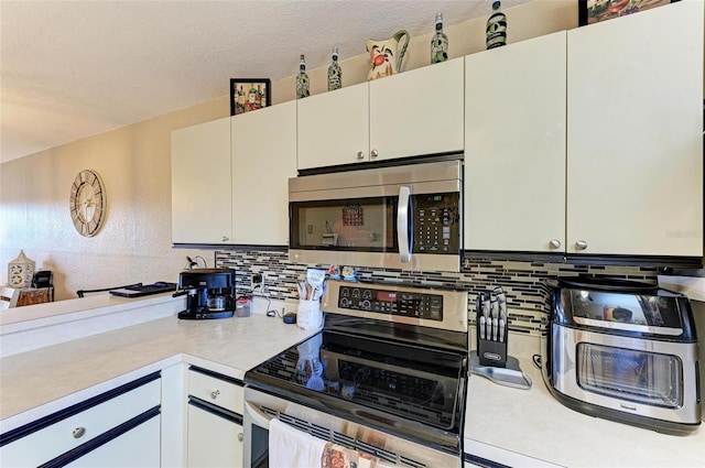 kitchen featuring white cabinets, a textured ceiling, decorative backsplash, and appliances with stainless steel finishes