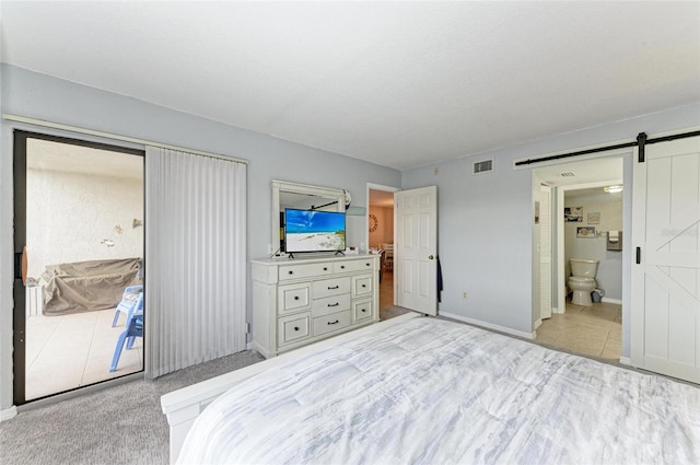 tiled bedroom featuring ensuite bathroom, access to outside, and a barn door