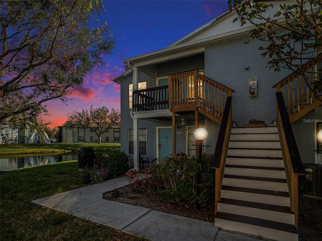 exterior space with a deck with water view, central air condition unit, and a yard