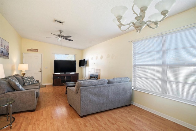 living room with ceiling fan with notable chandelier, light hardwood / wood-style floors, and lofted ceiling