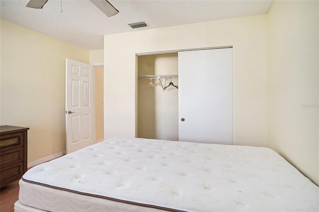 bedroom featuring a textured ceiling, wood-type flooring, ceiling fan, and a closet