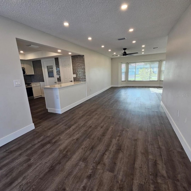 unfurnished living room featuring ceiling fan, dark hardwood / wood-style flooring, and a textured ceiling