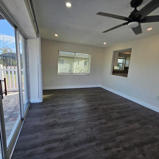 empty room featuring ceiling fan, dark wood-type flooring, and a textured ceiling