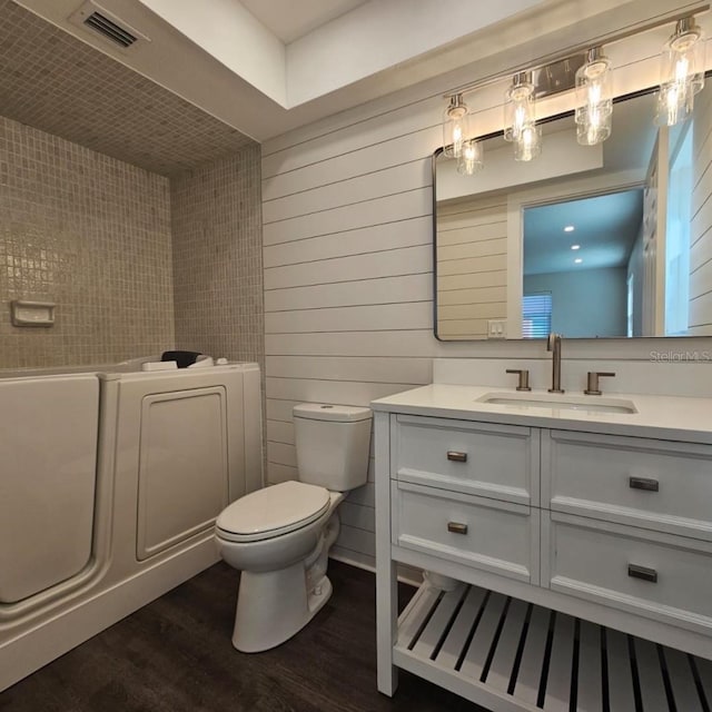 bathroom with wood walls, wood-type flooring, vanity, and toilet