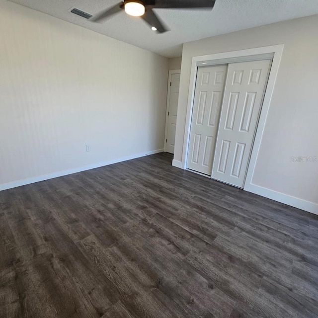 unfurnished bedroom featuring dark hardwood / wood-style flooring, a textured ceiling, a closet, and ceiling fan