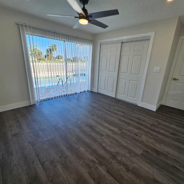 unfurnished bedroom with dark wood-type flooring, ceiling fan, a textured ceiling, access to outside, and a closet