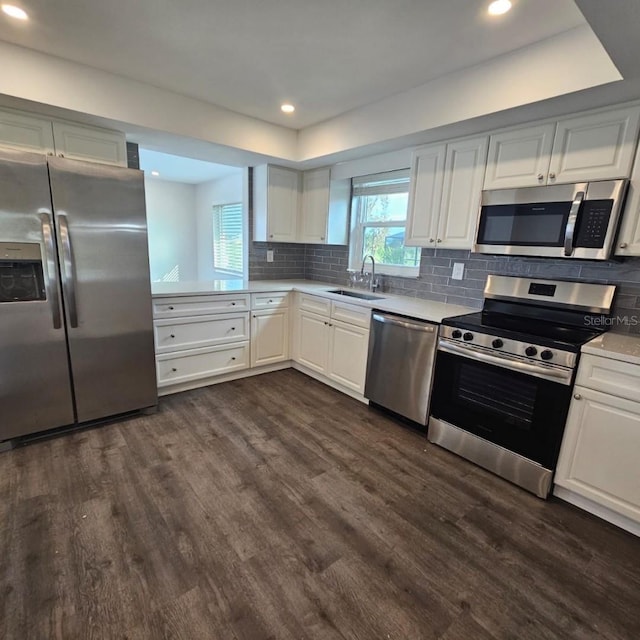 kitchen with sink, white cabinetry, appliances with stainless steel finishes, dark hardwood / wood-style flooring, and decorative backsplash