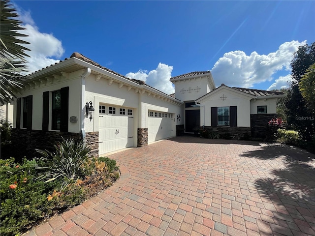 view of front of house with an attached garage, stone siding, a tiled roof, decorative driveway, and stucco siding