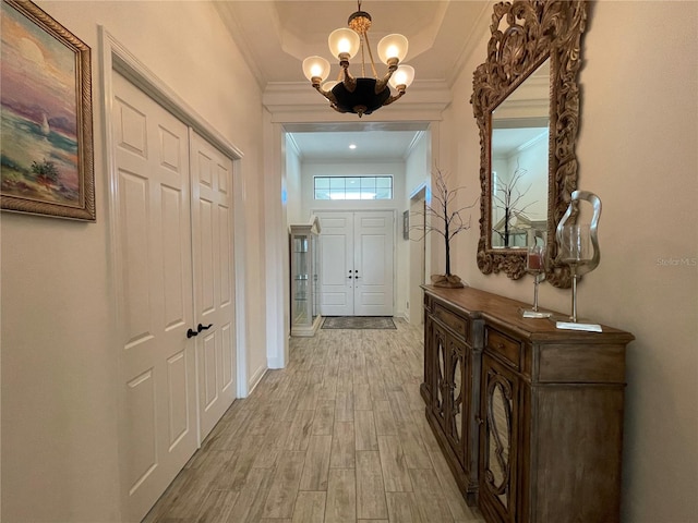 corridor with light hardwood / wood-style flooring, an inviting chandelier, and ornamental molding