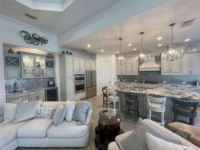 living room with light hardwood / wood-style floors, ornamental molding, sink, and beverage cooler