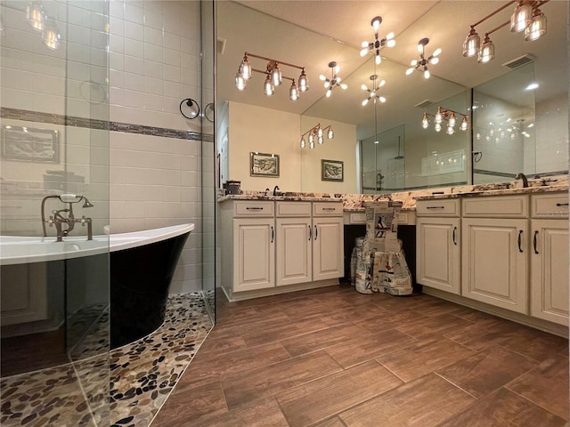 bathroom featuring a notable chandelier, vanity, tile walls, and plus walk in shower