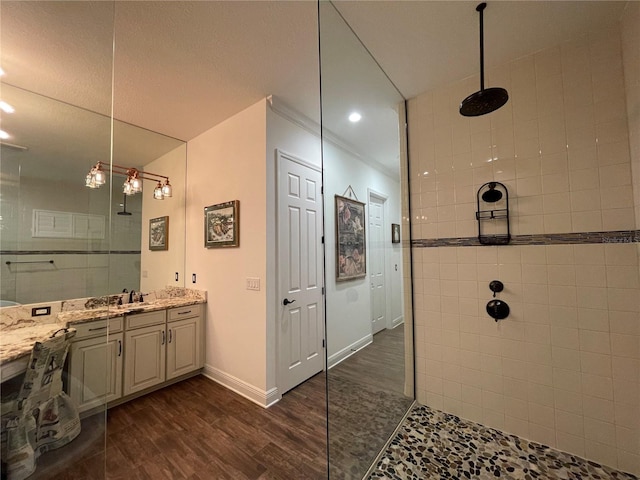 bathroom featuring hardwood / wood-style flooring, vanity, and tiled shower