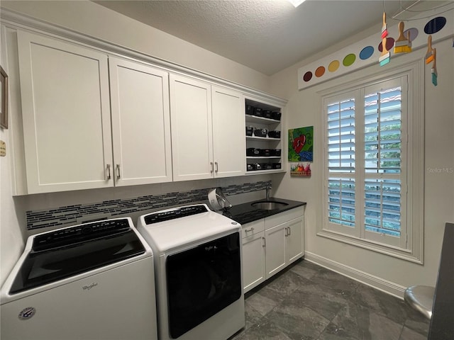 washroom featuring cabinets, a textured ceiling, washer and clothes dryer, and sink