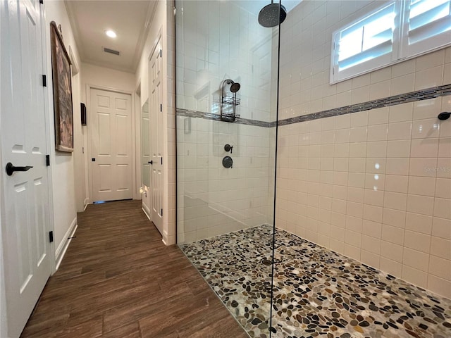 bathroom with hardwood / wood-style flooring and a tile shower