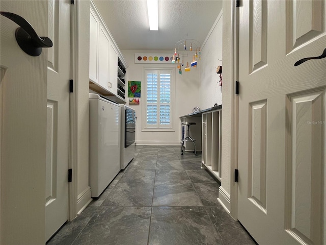 laundry area with washer and dryer, cabinet space, a textured ceiling, and baseboards