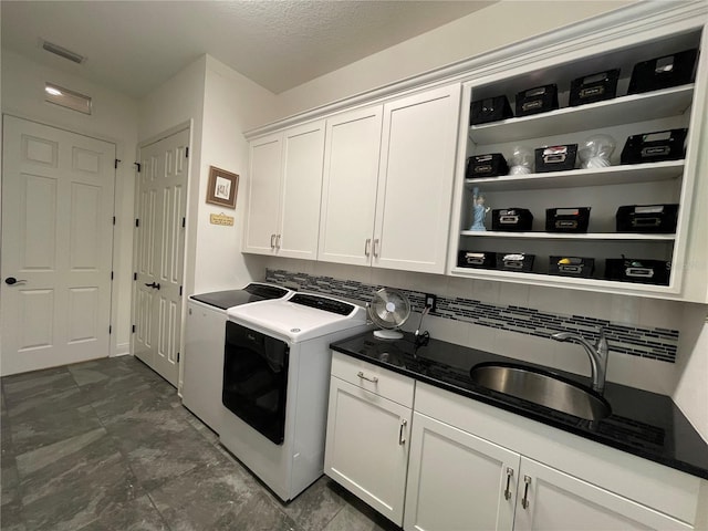 clothes washing area featuring cabinet space, a sink, visible vents, and washer and dryer