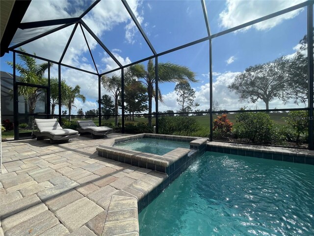 view of pool with a pool with connected hot tub, a lanai, and a patio