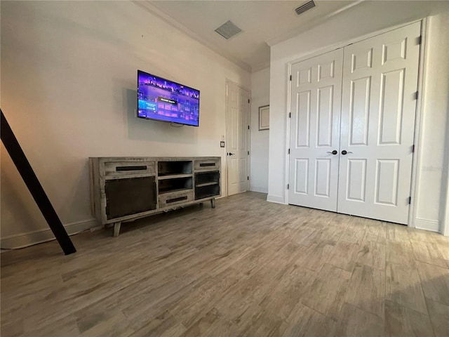 unfurnished bedroom with a closet, wood finished floors, visible vents, and baseboards