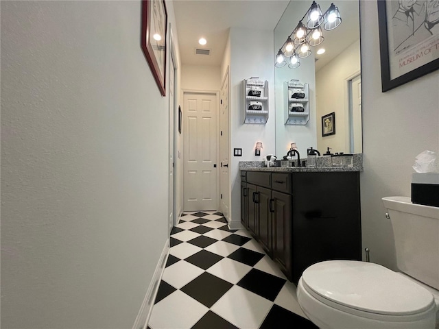 bathroom featuring double vanity, visible vents, toilet, baseboards, and tile patterned floors