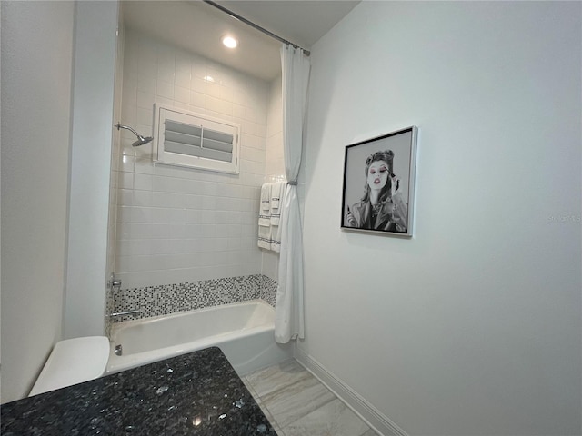 bathroom featuring marble finish floor, shower / bathtub combination with curtain, and baseboards