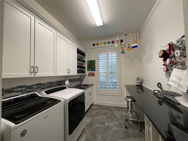 laundry room featuring washer and clothes dryer, cabinet space, a sink, a textured ceiling, and baseboards