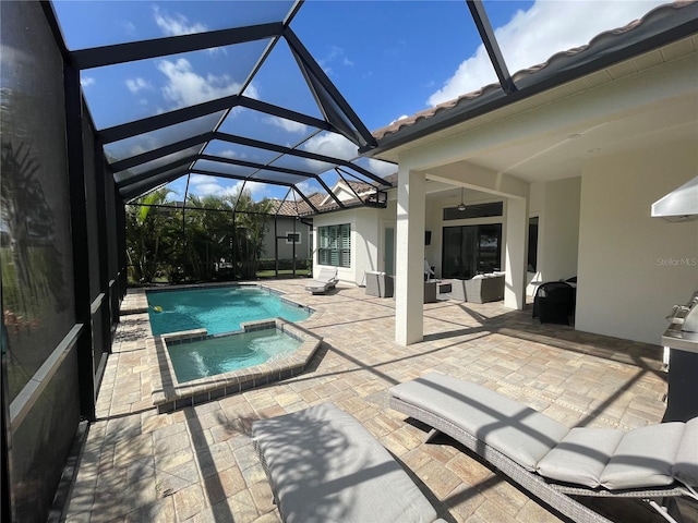 view of swimming pool with glass enclosure, a pool with connected hot tub, a patio area, and a ceiling fan