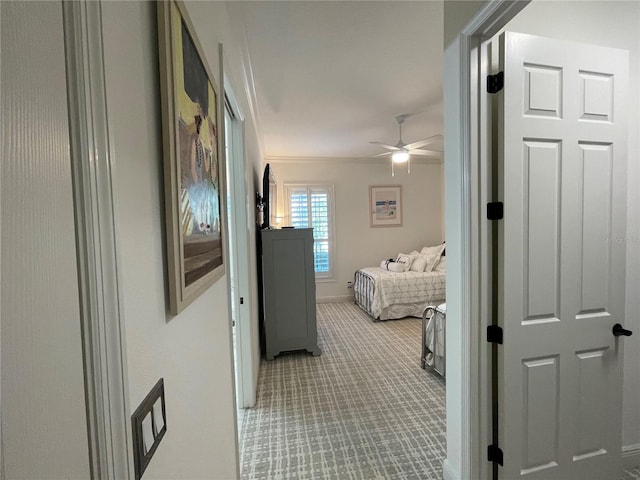 hall featuring crown molding, carpet, and baseboards