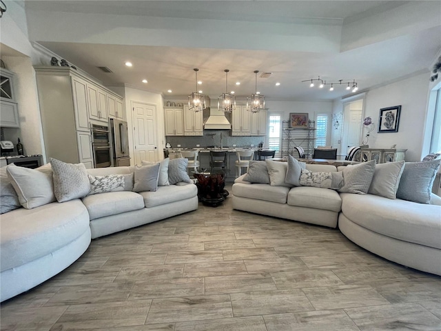 living room with a notable chandelier, crown molding, and recessed lighting