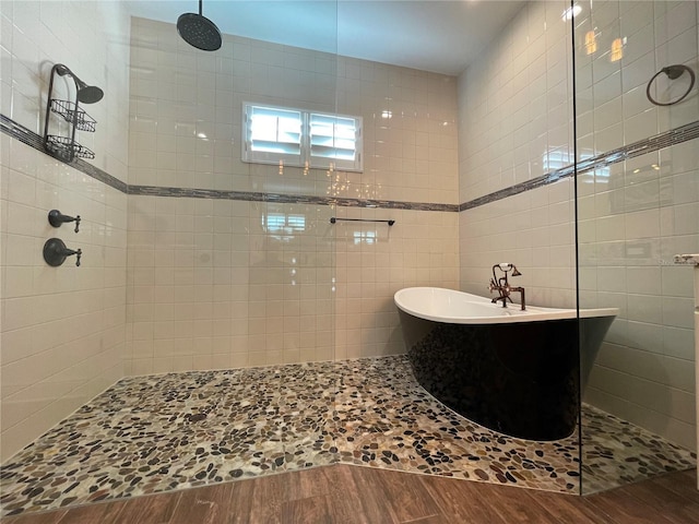 full bathroom with tile walls, a freestanding bath, wood finished floors, and a walk in shower