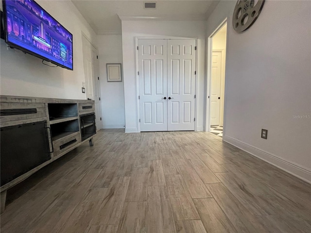 unfurnished living room featuring ornamental molding, baseboards, visible vents, and wood finished floors