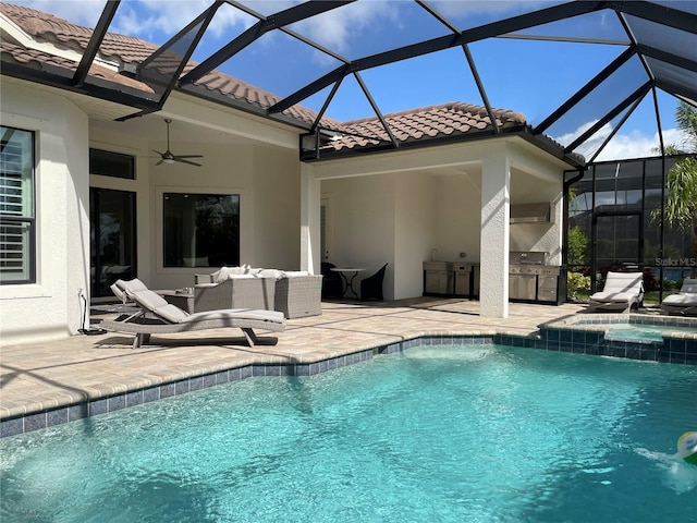 view of swimming pool featuring an outdoor kitchen, a patio, ceiling fan, a pool with connected hot tub, and glass enclosure