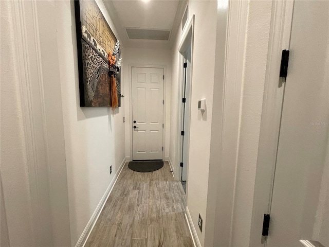 hall featuring light wood-style flooring and baseboards