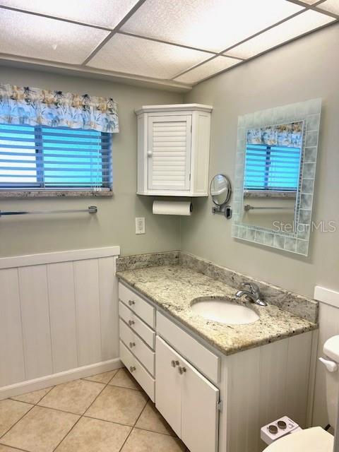 3751 S School Ave Unit 29, Sarasota, FL 34239 - bathroom featuring vanity, toilet, healthy amount of natural light, tile patterned floors, and a drop ceiling