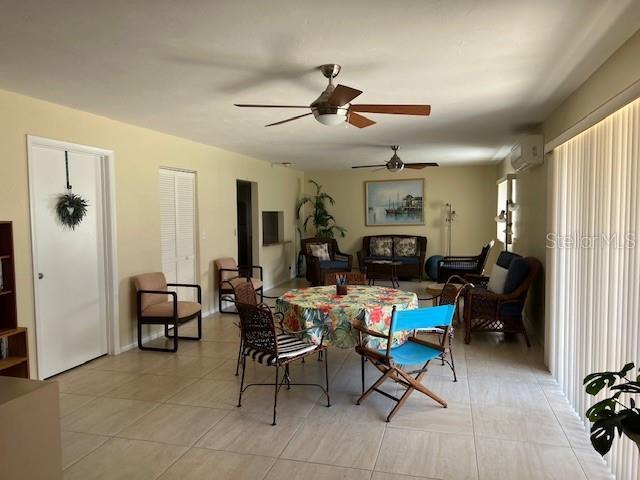 3751 S School Ave Unit 29, Sarasota, FL 34239 - dining space featuring ceiling fan, a wall mounted air conditioner, and light tile patterned flooring