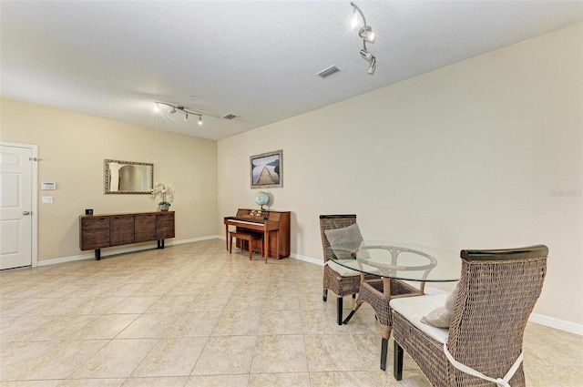 living area with a textured ceiling, track lighting, and light tile patterned floors