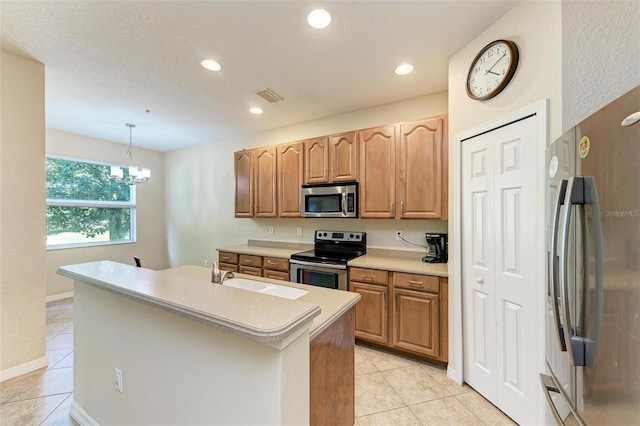 kitchen featuring a center island with sink, appliances with stainless steel finishes, hanging light fixtures, an inviting chandelier, and sink