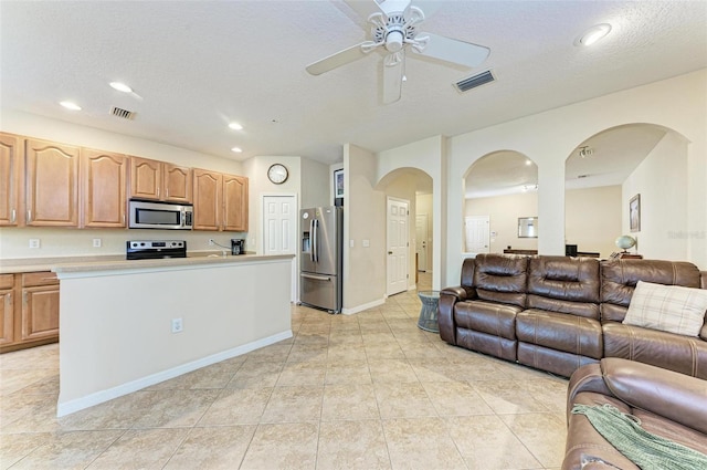 kitchen with ceiling fan, a textured ceiling, light tile patterned floors, and appliances with stainless steel finishes