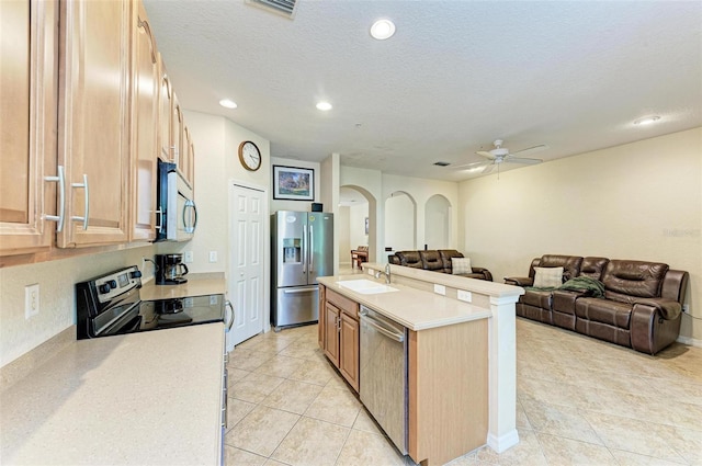 kitchen featuring appliances with stainless steel finishes, sink, a center island, a textured ceiling, and light brown cabinets