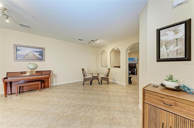 sitting room with a textured ceiling, rail lighting, and light tile patterned flooring