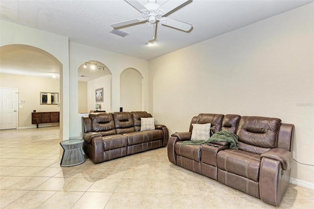 living room with light tile patterned flooring, ceiling fan, and a textured ceiling